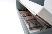 Polsterbett mit Stauraum, seitliche Perspektive, geöffnet mit Decken und Kissen im Inneren.