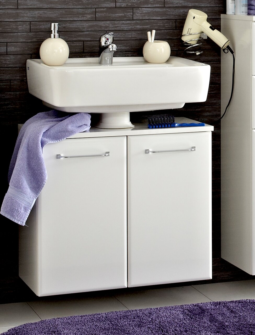 Moderner weißer Waschbeckenunterschrank mit zwei Türen, frontal fotografiert, unter einem Waschbecken montiert. Dekoriert mit einem lila Handtuch und Badezimmerutensilien.