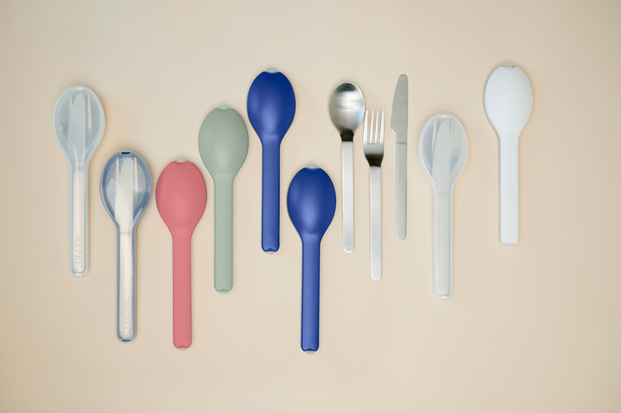 Mepal Besteck-Set 3-tlg. Nordic sage ELLIPSE Verschiedene Bestecksets in bunten Hüllen, darunter Löffel, Gabel und Messer, aus der Vogelperspektive auf einem beigen Hintergrund.