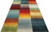 Bunter Teppich mit Patchwork-Quadraten und Farbverläufen in Rot, Blau, Grün, Gelb und Orange, perspektivische Ansicht von schräg oben