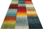 Kleurrijk tapijt met patchworkvierkanten en kleurverlopen in rood, blauw, groen, geel en oranje, perspectivisch aanzicht van schuin bovenaf