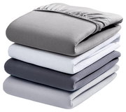 Gestapelte Spannbetttücher in verschiedenen Grautönen und Weiß, seitliche Perspektive