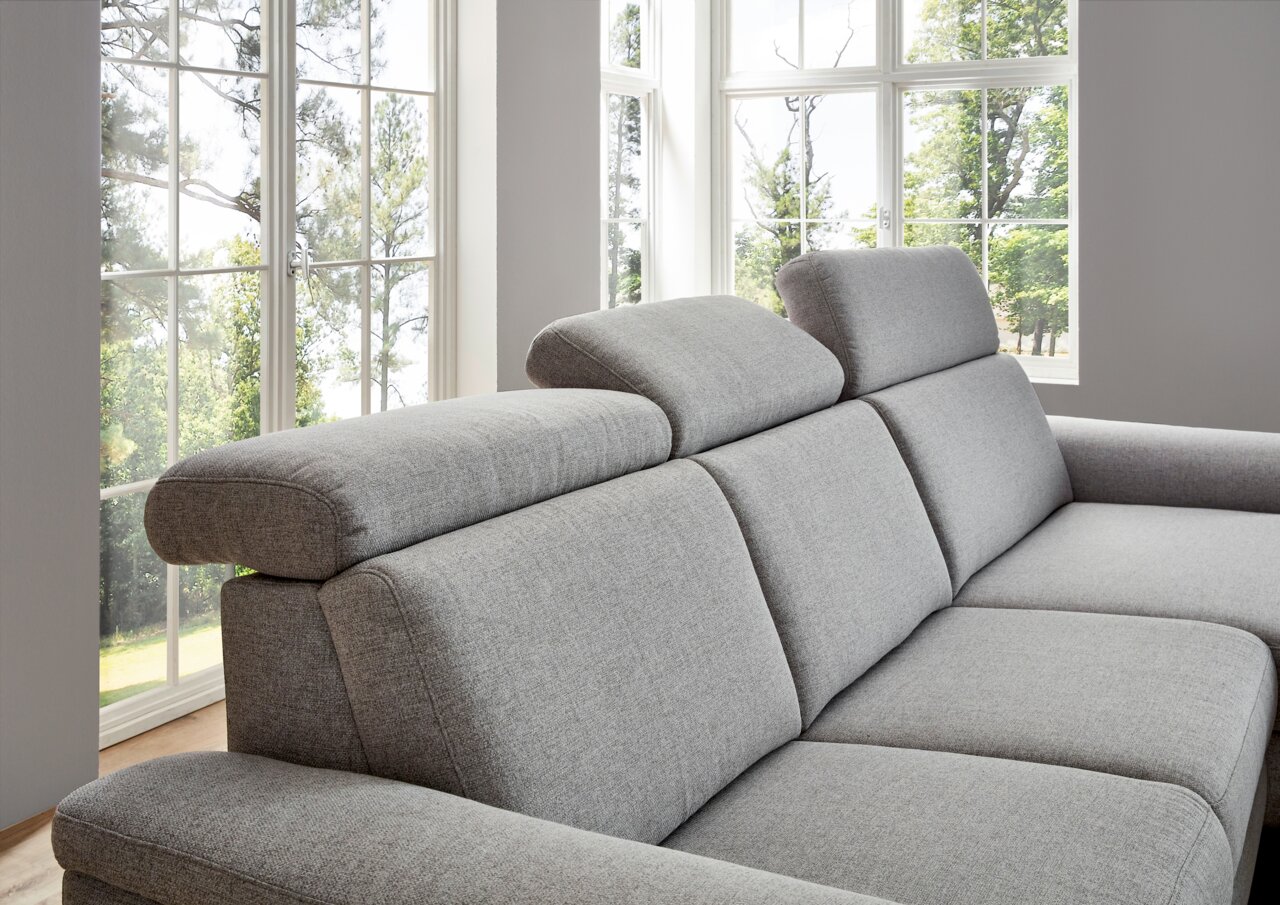 Graue Longchairkombination mit verstellbaren Kopfstützen, seitliche Perspektive vor großen Fenstern.