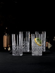 Vier elegante Trinkgläser mit Rautenmuster, gefüllt mit Getränken und Zitronenscheiben, auf einem dunklen Hintergrund. Frontale Perspektive.