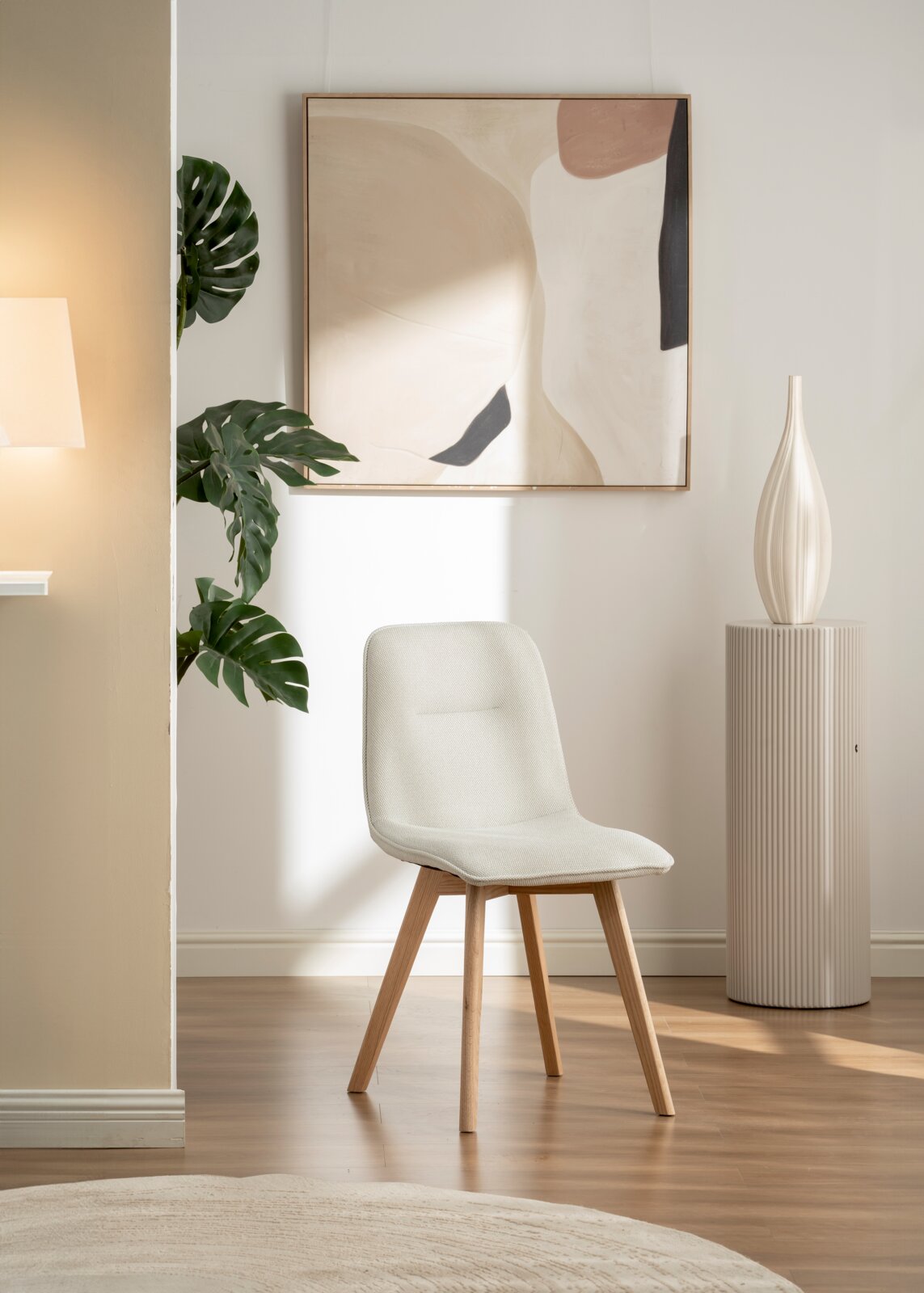 Moderner Stuhl mit hellem Stoffbezug und Holzbeinen, seitlich im Wohnzimmer platziert.