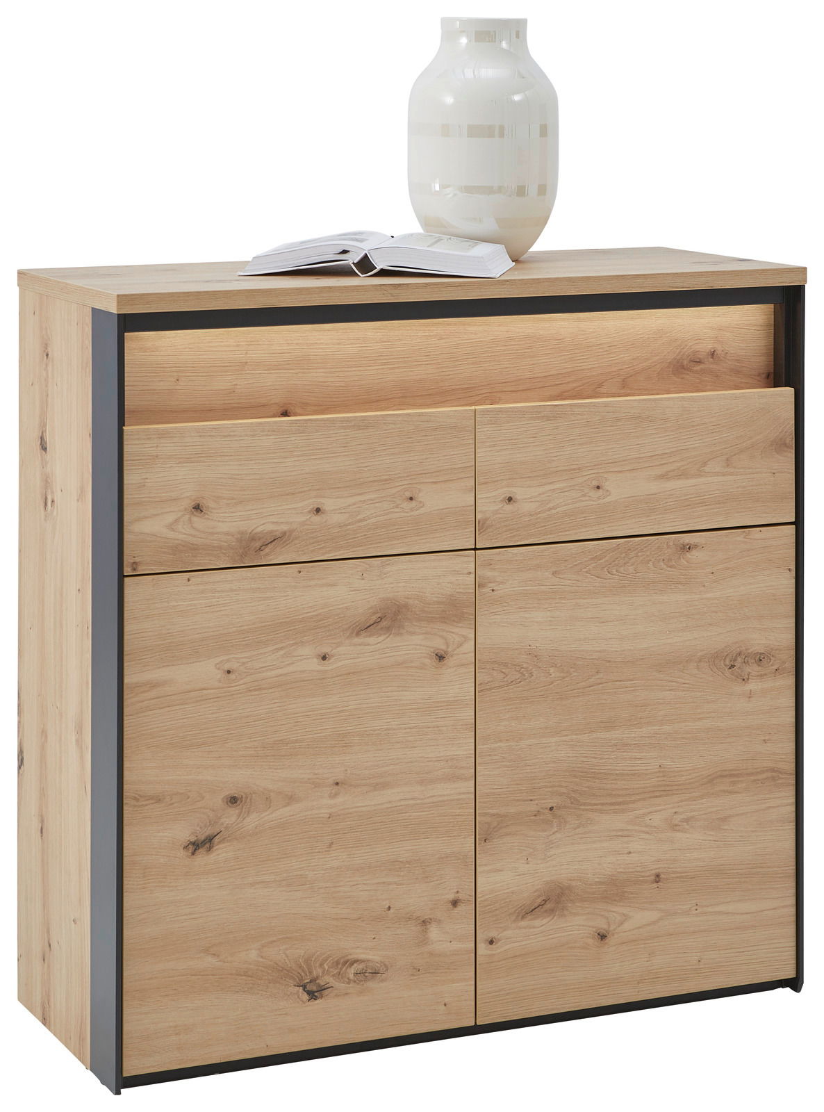 Kommode aus hellem Holz mit zwei Schubladen und zwei Türen, darauf eine weiße Vase und ein geöffnetes Buch, Perspektive von vorne links