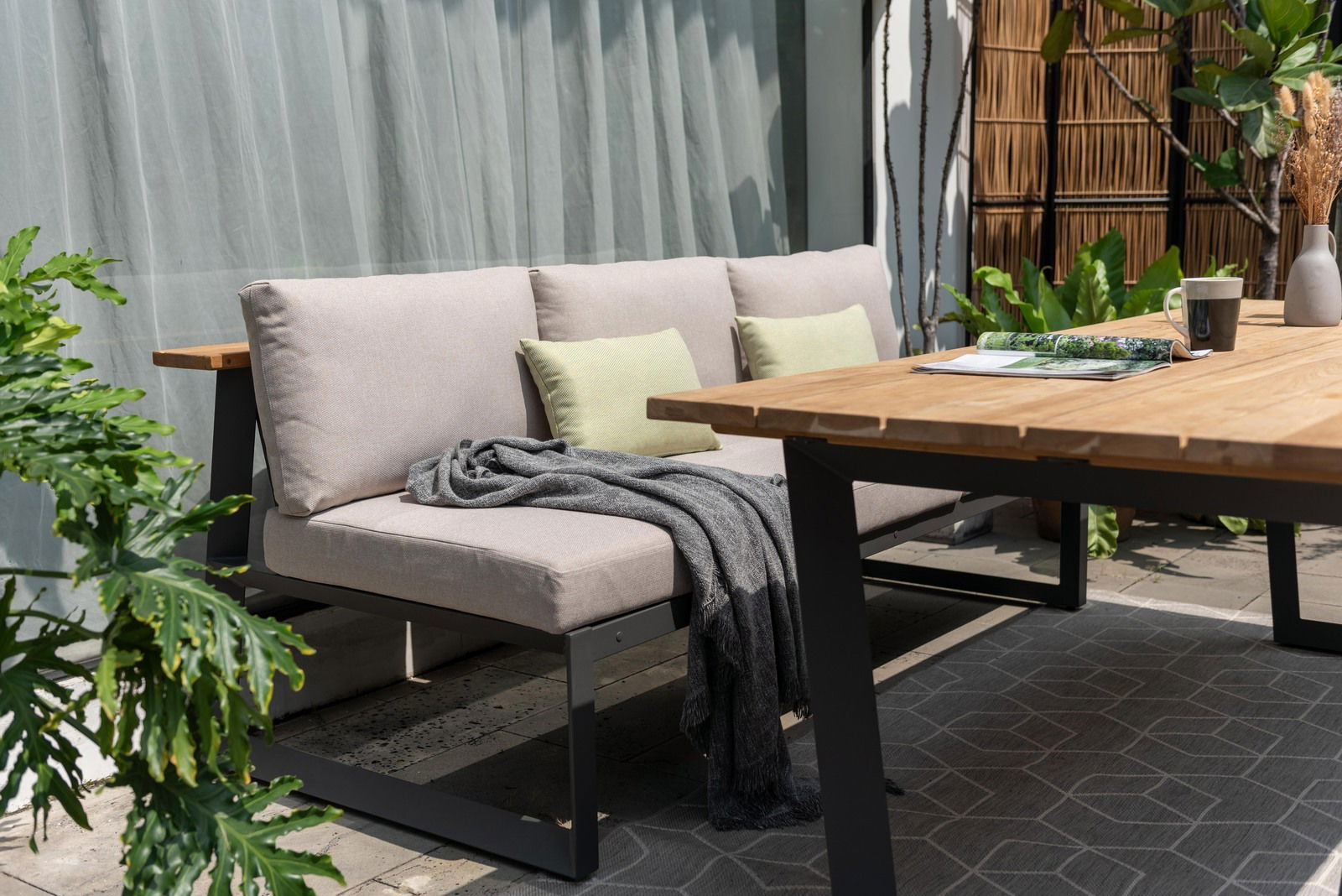 Gartensitzgruppe mit modernem Holztisch und bequemer Sitzbank, seitliche Perspektive