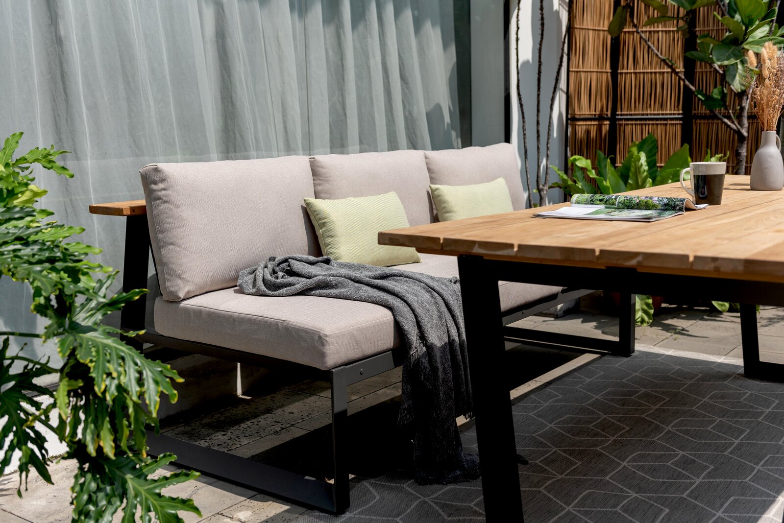 Gartensitzgruppe mit modernem Holztisch und bequemer Sitzbank, seitliche Perspektive