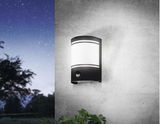 Moderne Wandleuchte 'CERNO' mit Bewegungssensor, montiert an einer Betonwand, seitliche Perspektive bei Nacht.