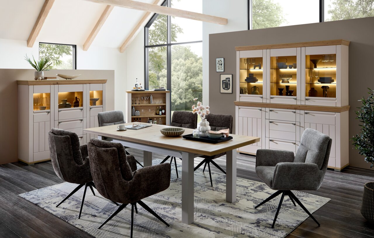 Landscape Buffetschrank COLMAR Esszimmer mit modernem Buffetschrank in heller Holzoptik, umgeben von großen Fenstern und gemütlichen Stühlen, aus der Perspektive des Raumes betrachtet.