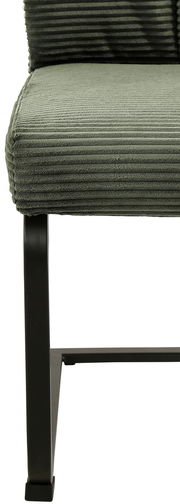 Nahaufnahme eines grünen Schwingstuhls mit geripptem Stoffbezug und schwarzem Metallgestell, seitliche Perspektive