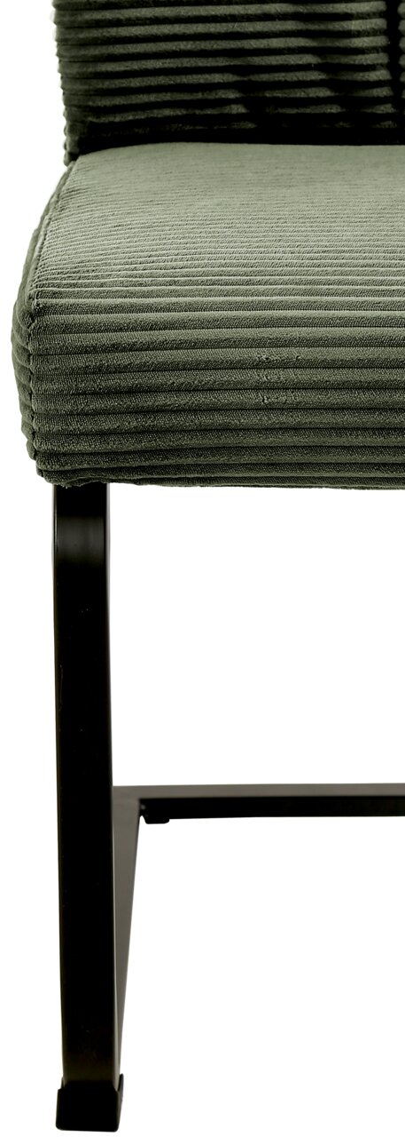 Nahaufnahme eines grünen Schwingstuhls mit geripptem Stoffbezug und schwarzem Metallgestell, seitliche Perspektive