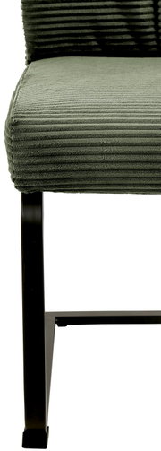 Close-up van een groene schommelstoel met geribbelde stoffen bekleding en een zwart metalen frame, gezien vanaf de zijkant