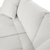 Nahaufnahme einer hellen, strukturierten Sofaecke mit Kissen, Perspektive von oben.
