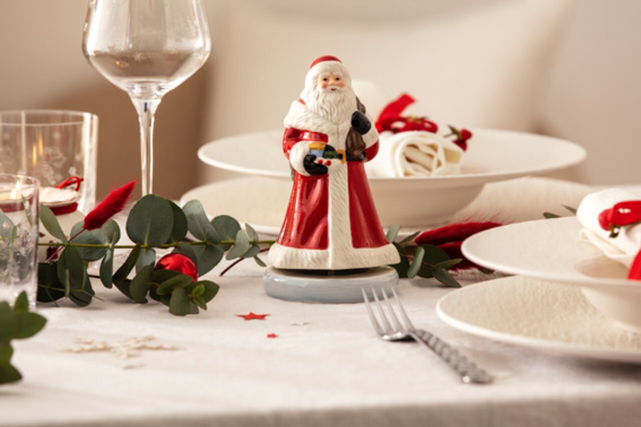 Draaiende muziekdoos met een kerstmanfiguur op een feestelijk gedekte tafel, gezien van voren.