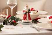 Draaiende muziekdoos met een kerstmanfiguur op een feestelijk gedekte tafel, gezien van voren.