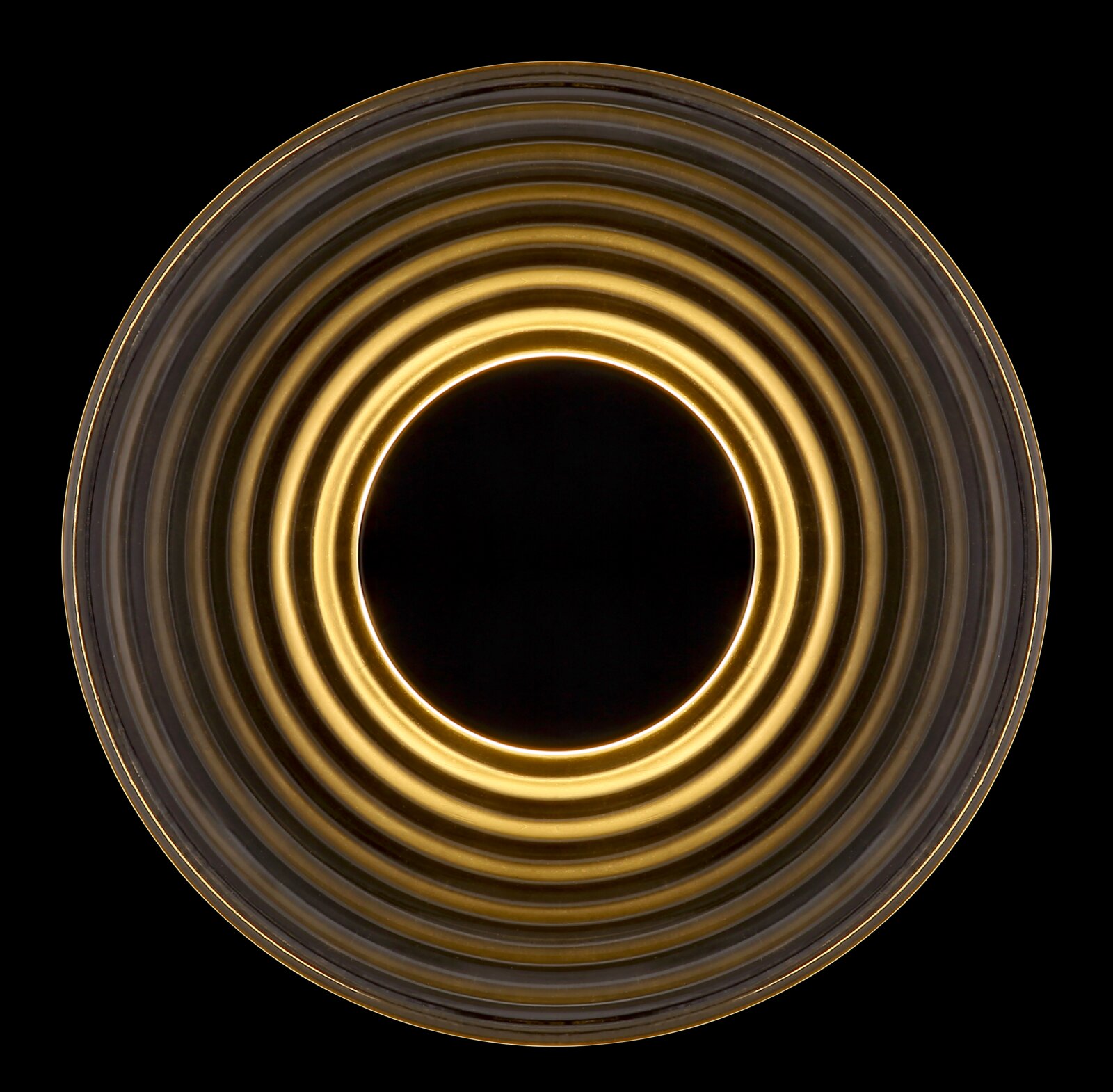 Rundes, geripptes Glas- oder Lampenschirm-Element in Amber-/Goldoptik mit konzentrischen Ringen, Draufsicht von oben auf schwarzem Hintergrund