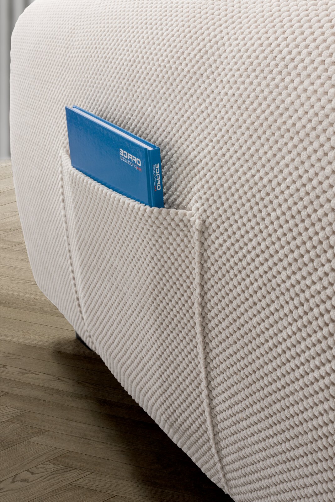 Close-up van een gestructureerde, crèmekleurige hoekbank met een handig zijvak waarin een blauw boek ligt, op een houten vloer.