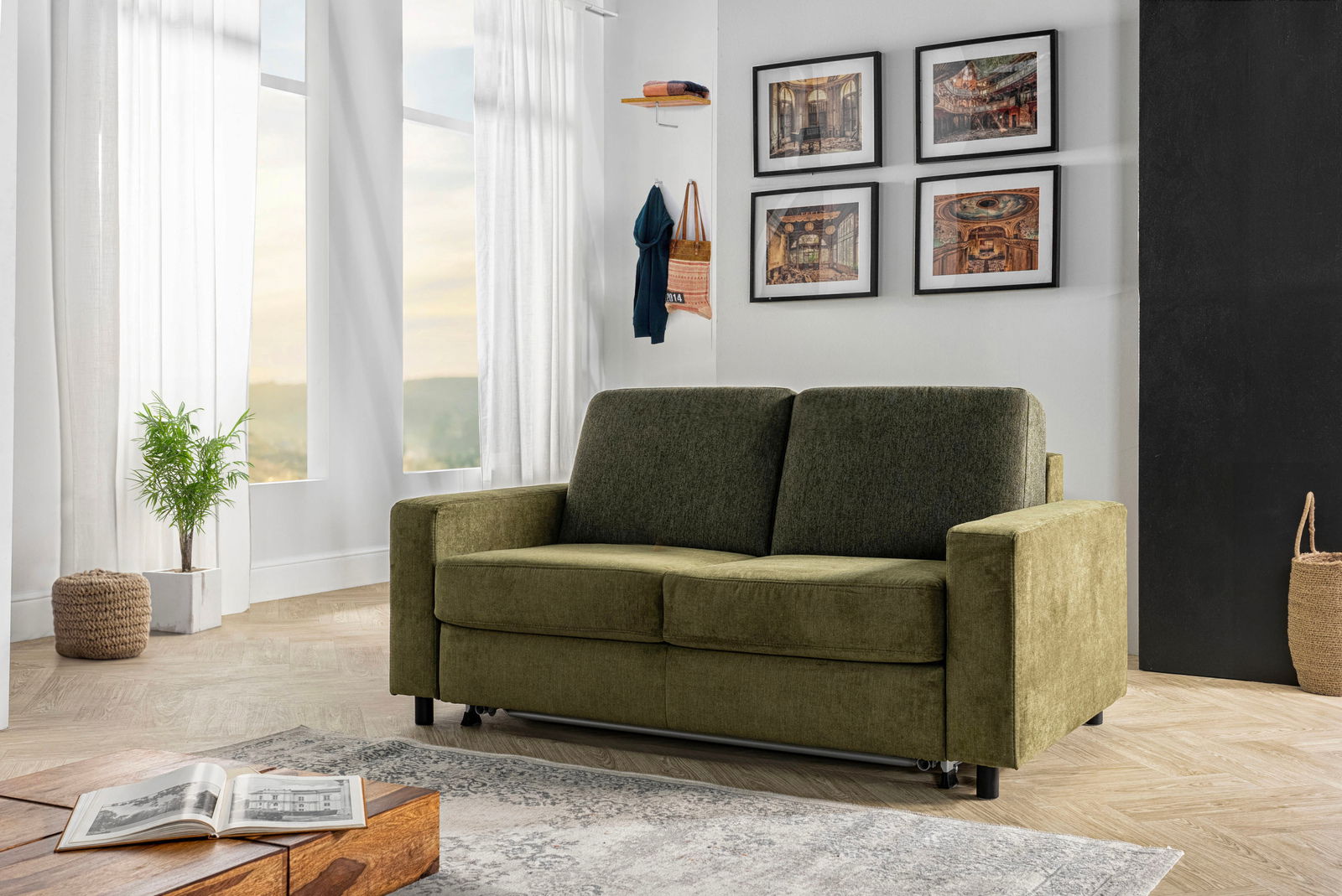 Grünes Funktionssofa in einem modernen Wohnzimmer, frontal betrachtet, mit dekorativen Elementen wie Pflanzen und Bildern an der Wand.