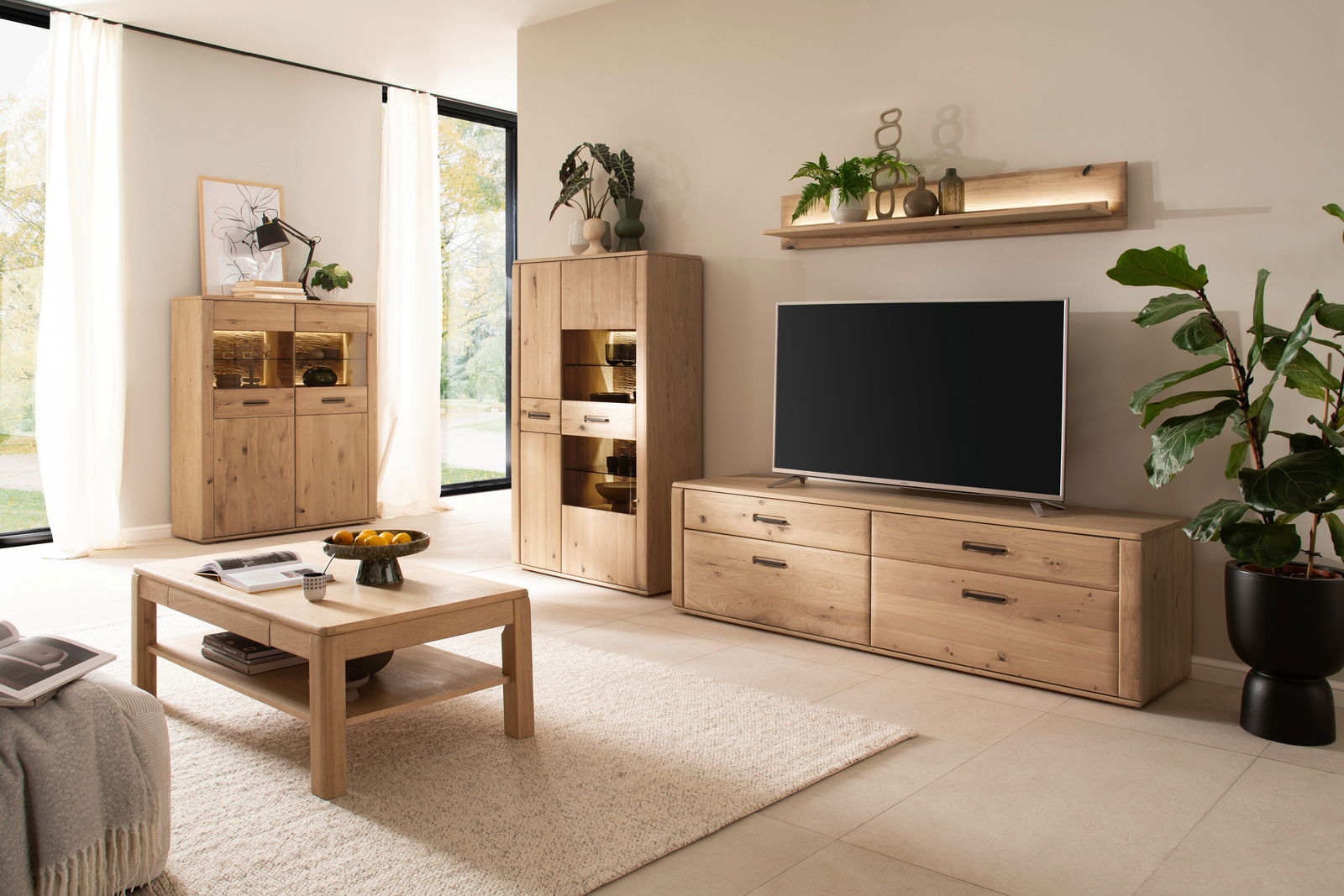 Zurbrüggen Wandboard ALENTO Wohnzimmer mit modernen Holzmöbeln, darunter ein TV-Element, ein Highboard und ein Wandboard, aus hellem Holz. Perspektive von vorne.