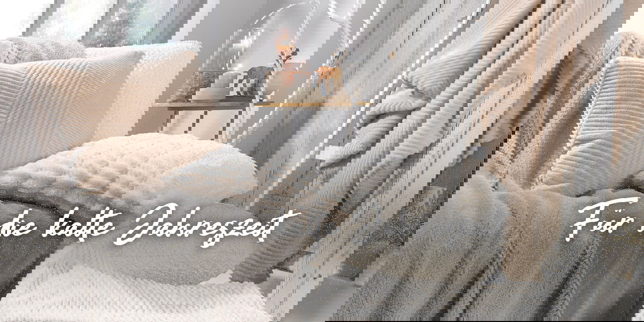 Gemütliche Kissen und Decken in warmen Tönen, darüber Schriftzug 