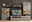 Moderne Wohnwand in grauem Design mit Holzdetails, bestehend aus einem TV-Schrank, zwei Vitrinen und einem Wandregal, frontal betrachtet.
