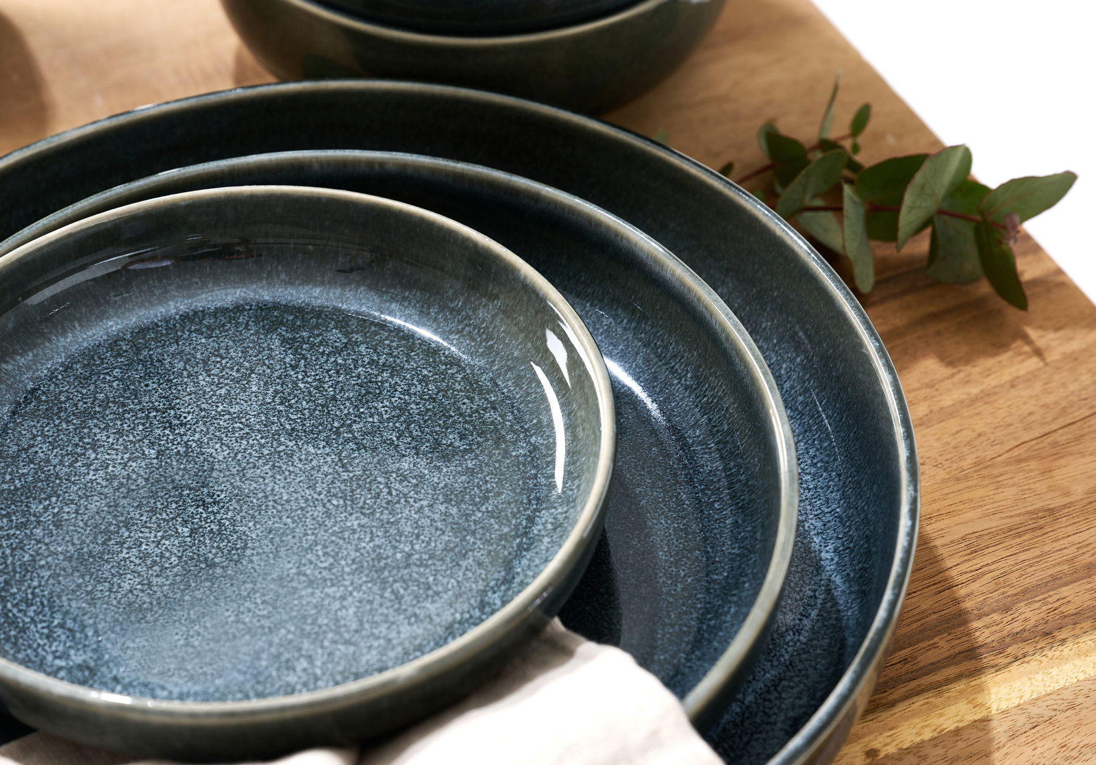 Ritzenhoff & Breker Dessertteller EDA SCHIEFER Nahaufnahme von übereinander gestapelten, dunkelblauen Tellern mit glatter, glänzender Oberfläche auf einem Holztisch, seitliche Perspektive.