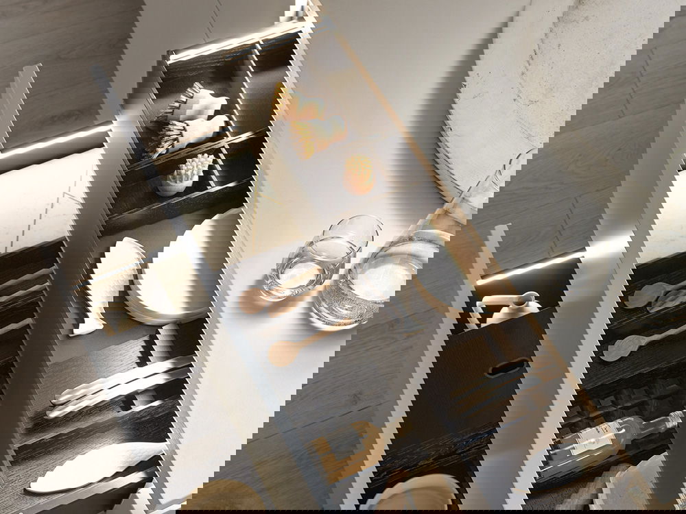 Geöffnete Küchenschubladen mit Holz- und Metallbesteck, Bürsten und LED-Beleuchtung in modernem Design.