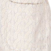 Nahaufnahme eines cremefarbenen Kapuzenmantels mit Zopfmuster.