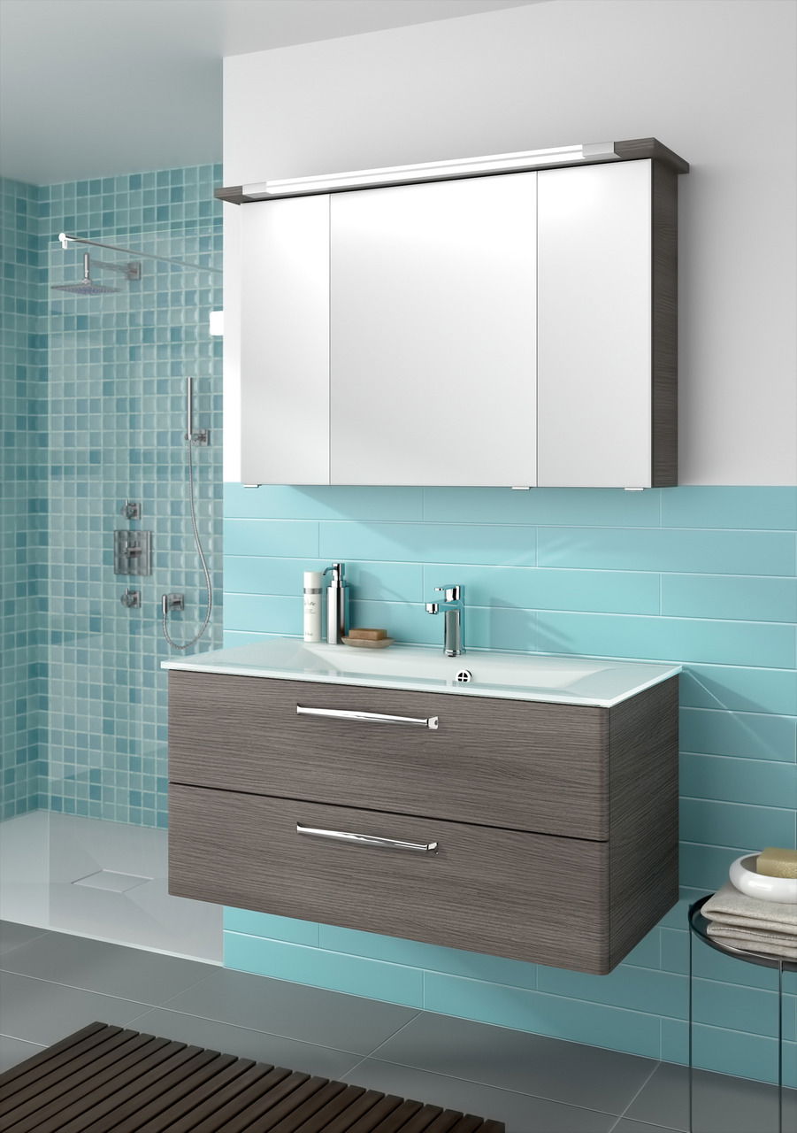 Moderner Badblock mit zwei Schubladen in Holzoptik und weißem Waschbecken, frontal betrachtet, vor einer türkisfarbenen Wand.