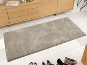 Beige Uni-Teppich in rechteckiger Form, aus der Vogelperspektive fotografiert, auf hellem Holzboden vor einem Sideboard platziert.