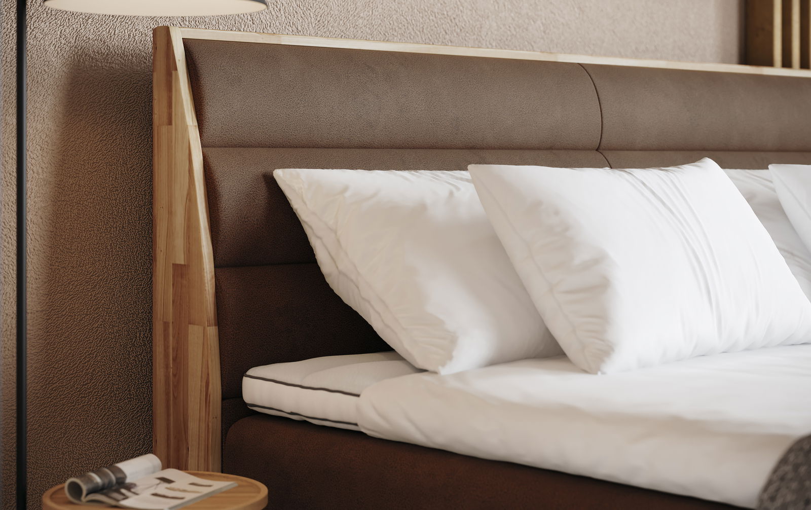 Nahaufnahme eines Boxspringbetts mit braunem Kopfteil und weißen Kissen, seitliche Perspektive
