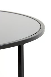 Nahaufnahme eines modernen Couchtisches mit schwarzer, runder Tischplatte und schlankem Metallrahmen, seitliche Perspektive