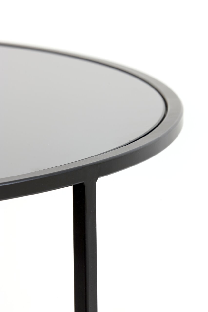 Nahaufnahme eines modernen Couchtisches mit schwarzer, runder Tischplatte und schlankem Metallrahmen, seitliche Perspektive