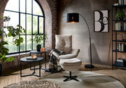 Moderner Relaxsessel mit Hocker in einem stilvollen Wohnzimmer, seitliche Perspektive.