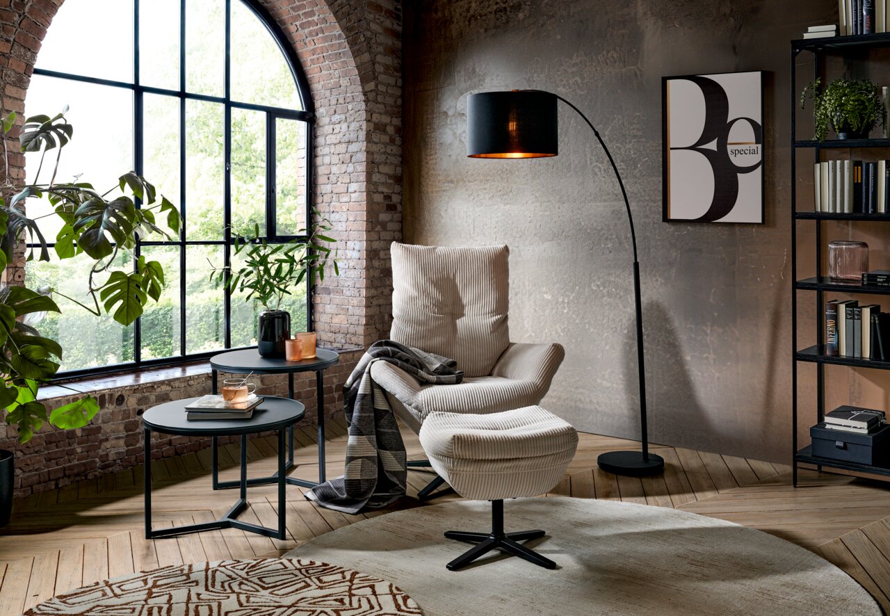 Moderne relaxfauteuil met voetenbank in een stijlvolle woonkamer, gezien vanaf de zijkant.