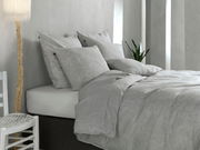 Graue Bettwäsche mit Paisley-Muster auf einem Bett, seitliche Perspektive