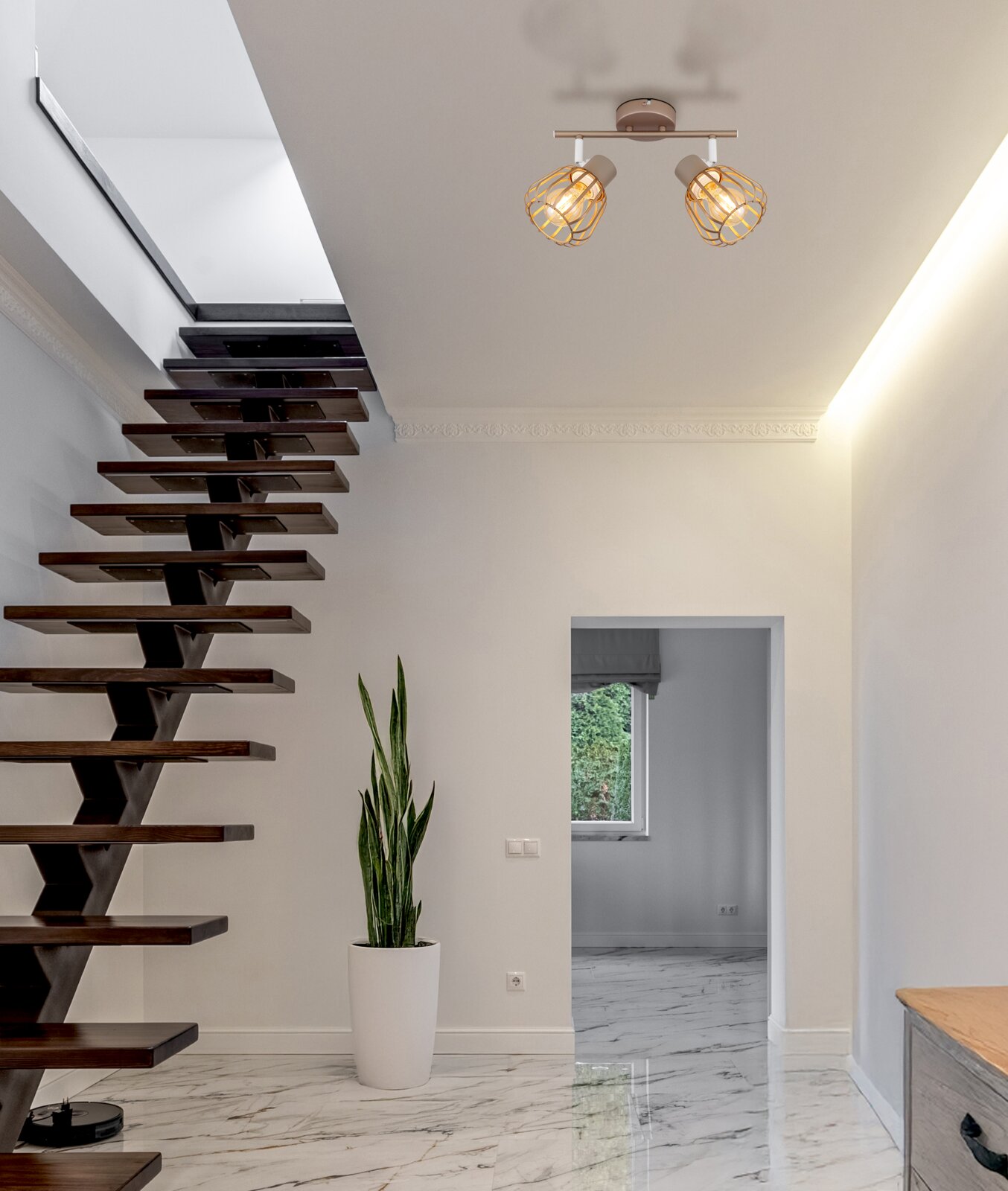 Moderne Deckenleuchte mit zwei schwenkbaren Spots und goldfarbenen Drahtkäfig-Schirmen, warm leuchtend, in einem hellen Flur neben einer Holztreppe – Ansicht von unten nach oben zur Decke.