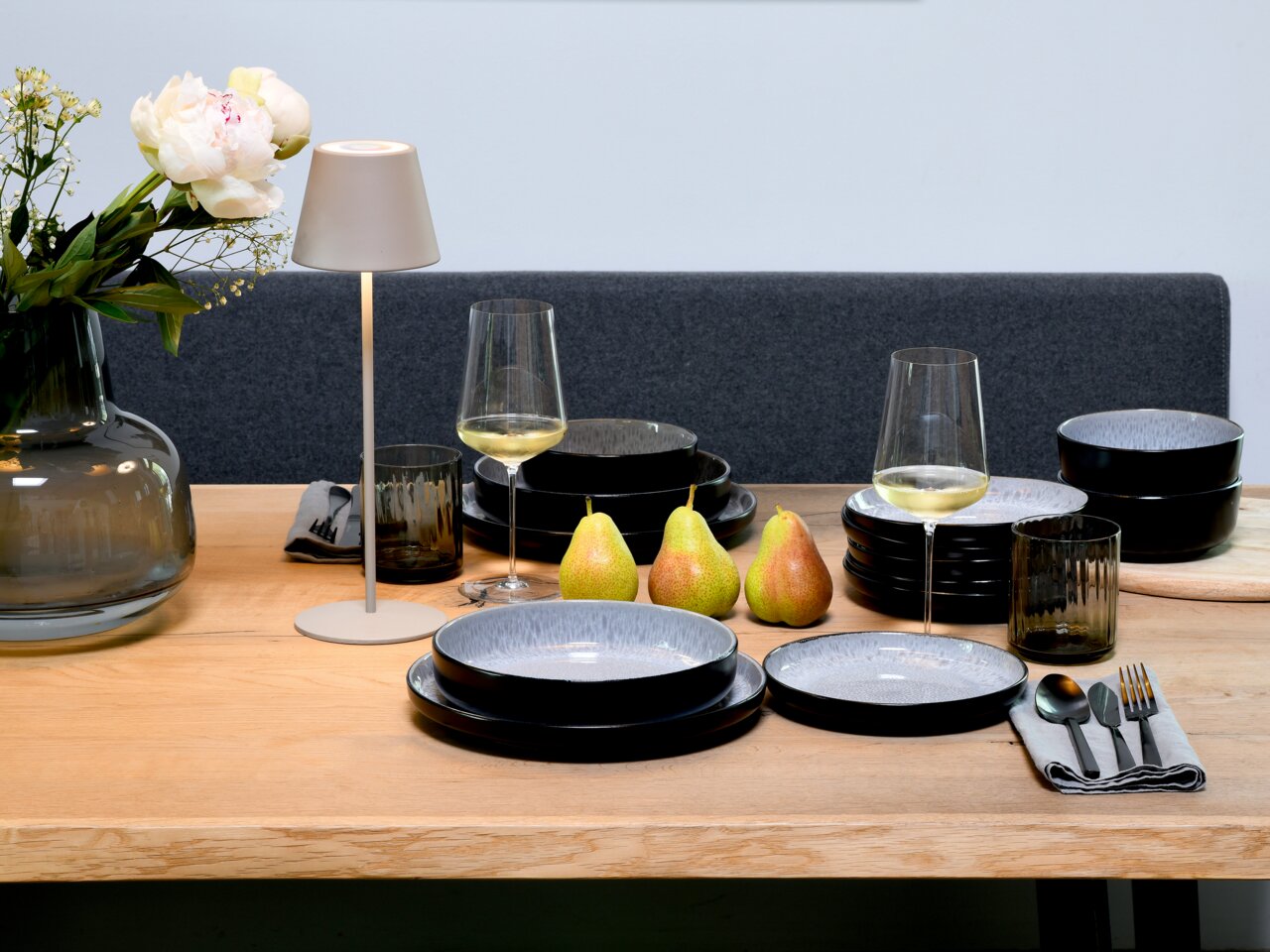 creaTable Tellerset 18-tlg. Frost NORDIC FJORD Tellerset 18-tlg. Frost auf einem gedeckten Tisch mit modernen, schwarzen und grauen Tellern, Weingläsern und Besteck, aus der Perspektive von vorne.