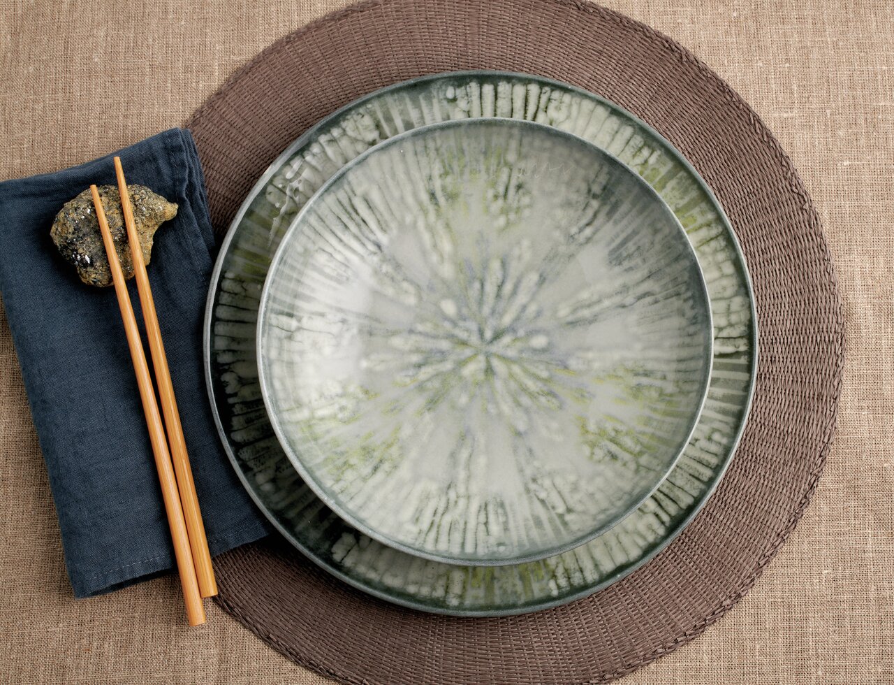 Arthur Krupp Tellerset Fusion Grey 12-tlg. Vogelperspektive auf ein Tellerset Fusion Grey mit zwei Tellern, Essstäbchen und einem Stein auf einem Stoffserviette.