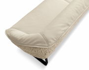 Nahaufnahme einer cremefarbenen Bank mit weicher Polsterung und schwarzem Metallfuß, seitliche Perspektive.