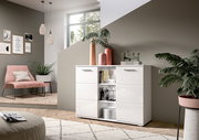Moderne weiße Kommode mit glänzender Oberfläche, frontal fotografiert in einem stilvoll eingerichteten Wohnzimmer mit Pflanzen und Dekorationen.