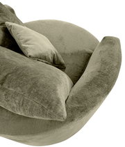 Nahaufnahme eines grünen Sessels mit weichem Stoffbezug und passendem Kissen, seitliche Perspektive