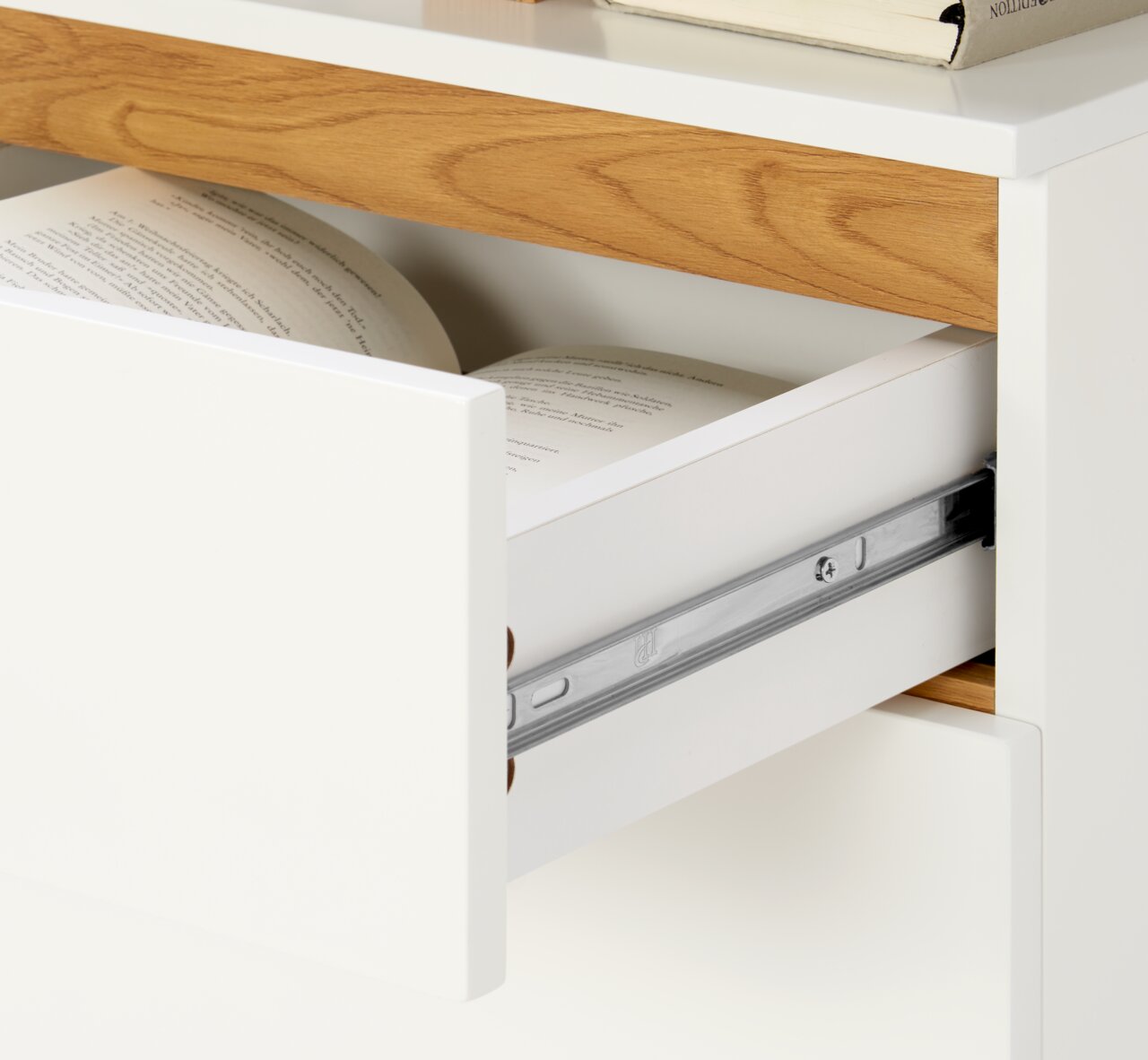 Nahaufnahme eines Schreibtischs mit einer geöffneten Schublade, die Bücher enthält. Die Perspektive zeigt die rechte Seite des Schreibtischs.