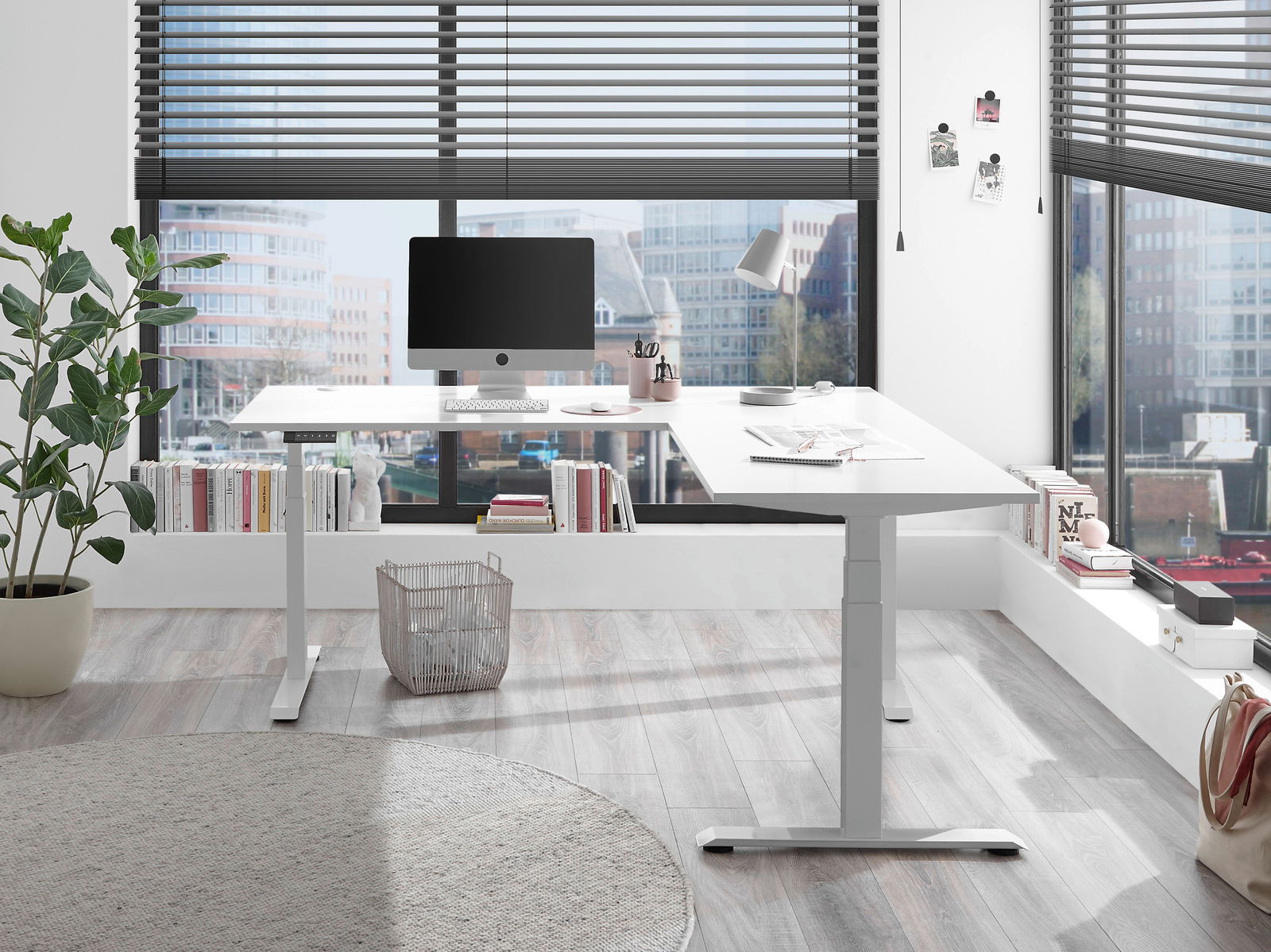 Moderner weißer E-Eckschreibtisch in einem hellen Büro mit Blick auf die Stadt, von vorne betrachtet.