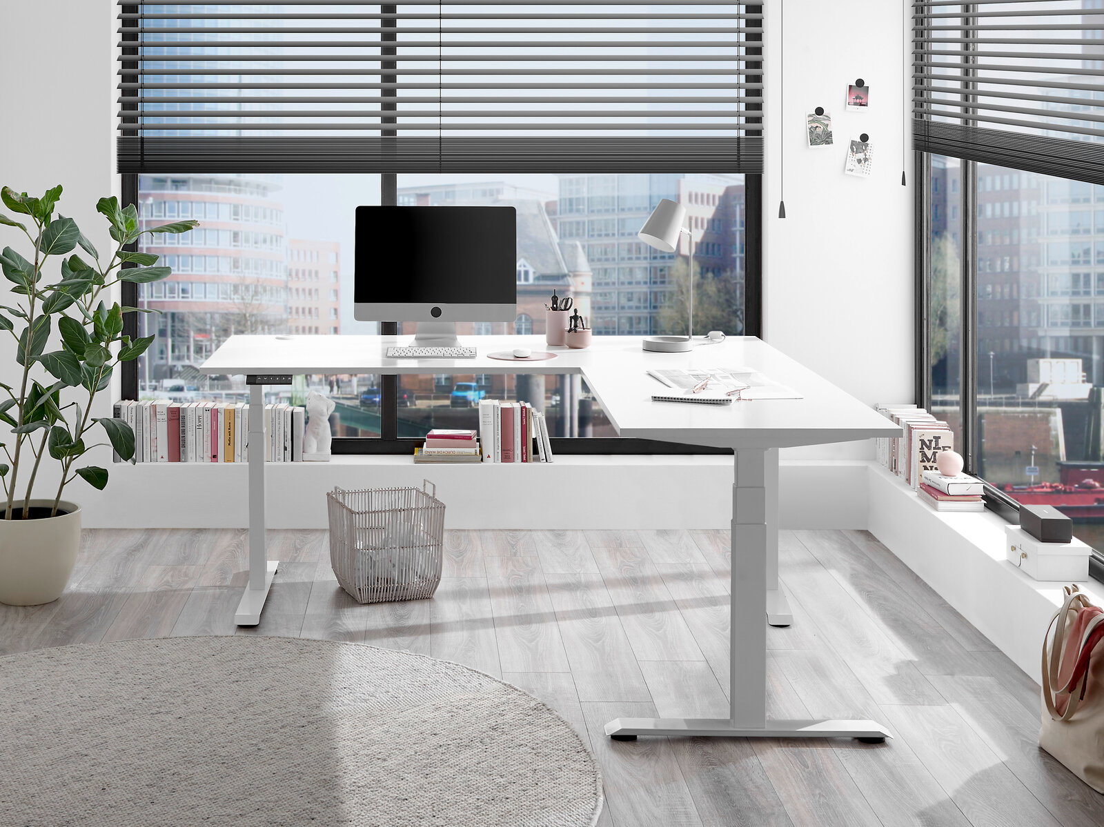 Moderner weißer E-Eckschreibtisch in einem hellen Büro mit Blick auf die Stadt, von vorne betrachtet.