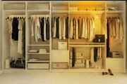 Ein geöffneter Kleiderschrank mit verschiedenen Kleidungsstücken und Accessoires, beleuchtet von einem Akku-Leuchtmittel aus der Perspektive von vorne.