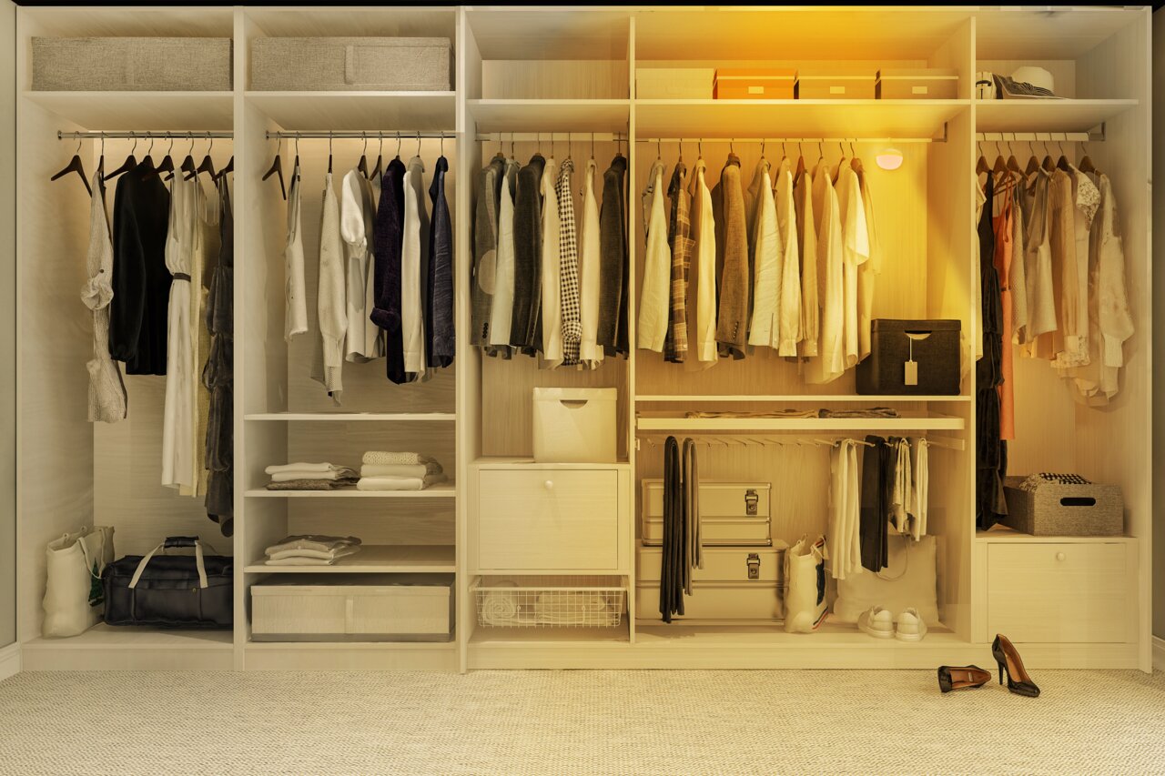 Een open kledingkast met diverse kledingstukken en accessoires, verlicht door een acculamp, gezien vanuit het vooraanzicht.