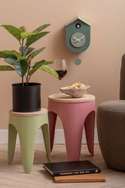 Grüne Wanduhr im Kuckucksuhren-Stil von KARLSSON, an einer beige gestrichenen Wand hängend, mit einem modernen, minimalistischen Design. Perspektive: Frontalansicht.