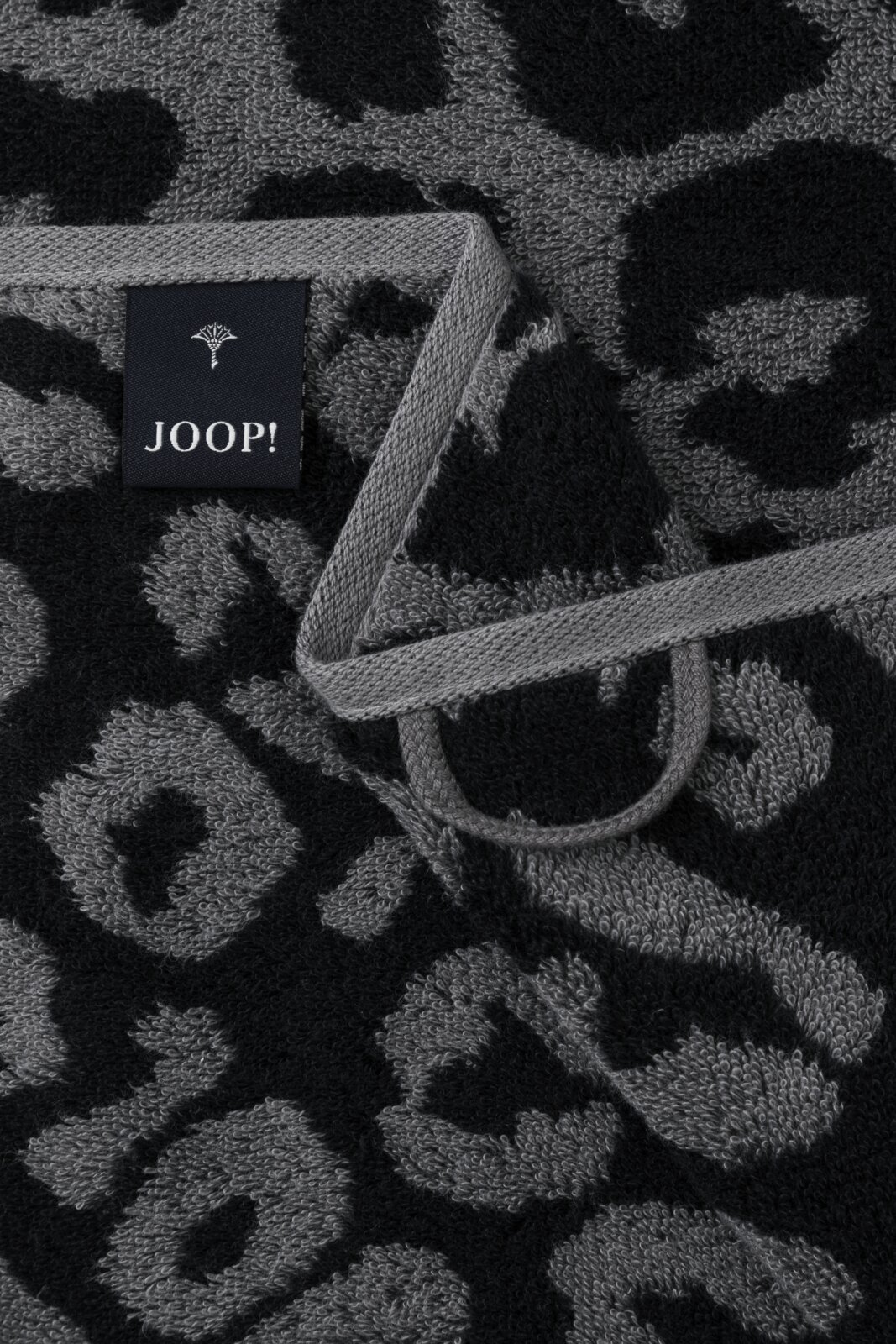 Nahaufnahme eines Handtuchs mit grauem und schwarzem Leopardenmuster und einem JOOP!-Label.